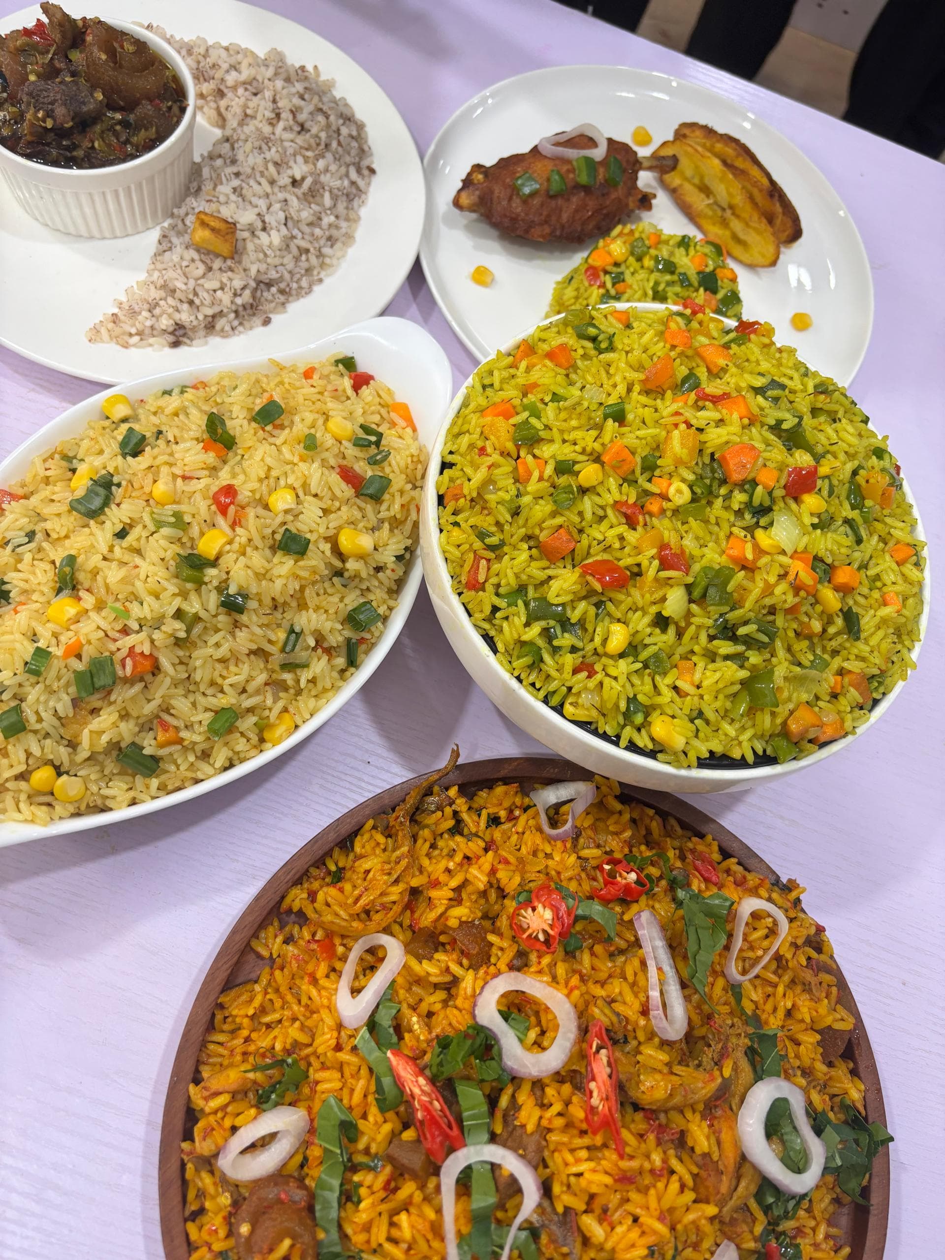 Steaming Jollof Rice — vibrant orange rice garnished with fresh herbs and grilled chicken on a rustic clay plate